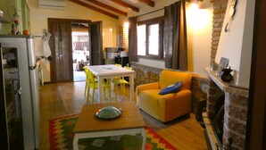 A cozy living room with a wooden ceiling, a dining area with yellow chairs, and a fireplace. - Scappo in Umbria, La casa verde di Eva (Amelia)