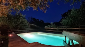 An outdoor swimming pool at dusk with a wooden deck and a wooden fence. - Scappo in Umbria, La casa verde di Eva (Amelia)