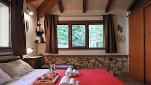 A hotel room with a bed, a wooden headboard, a stone wall, a window with curtains, and a tray with towels and glasses. - Scappo in Umbria, La casa verde di Eva (Amelia)