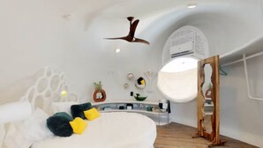 Un dormitorio moderno con una cama curvada, un ventilador de techo y un sistema de aire acondicionado integrado.