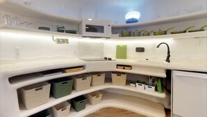 Una cocina con armarios blancos, un microondas y varios utensilios de cocina.