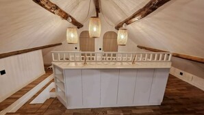Un baño blanco y rectangular con suelo de madera, un banco blanco y tres lámparas colgantes.