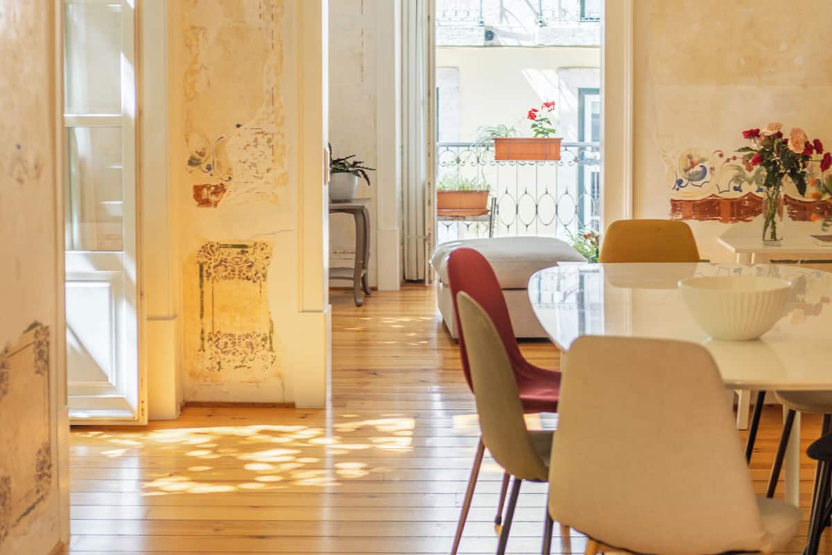 Een eetruimte met een houten vloer, een tafel met stoelen en hangende吊灯.