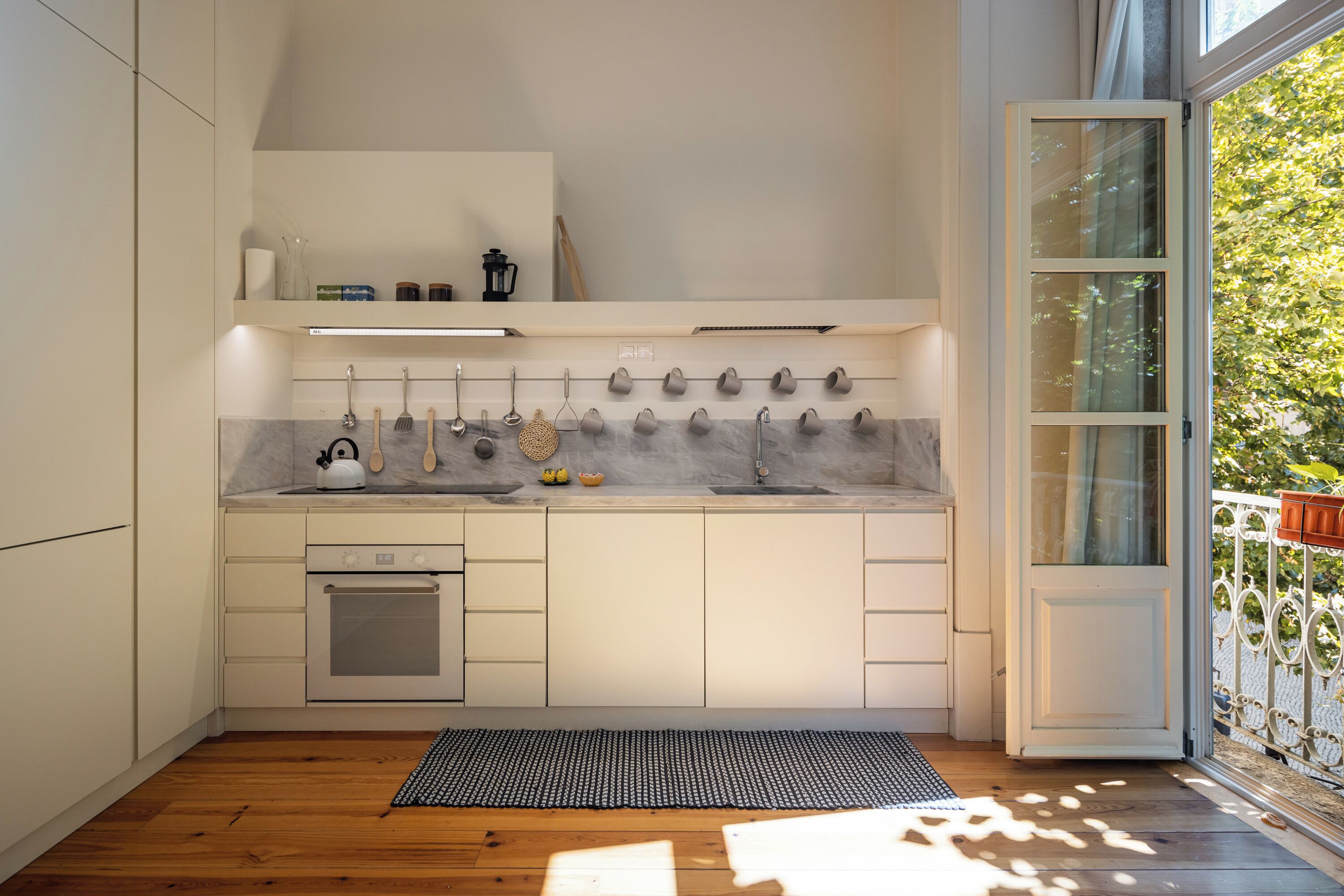 A modern kitchen with a built-in oven, a sink, and a hanging utensil rack.