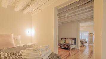 Un dormitorio con cama, una mesita de noche, una lámpara y vistas a otra habitación.