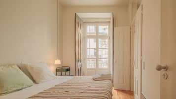 Un dormitorio con una cama, una mesita de noche, una lámpara y una puerta que da a un balcón.