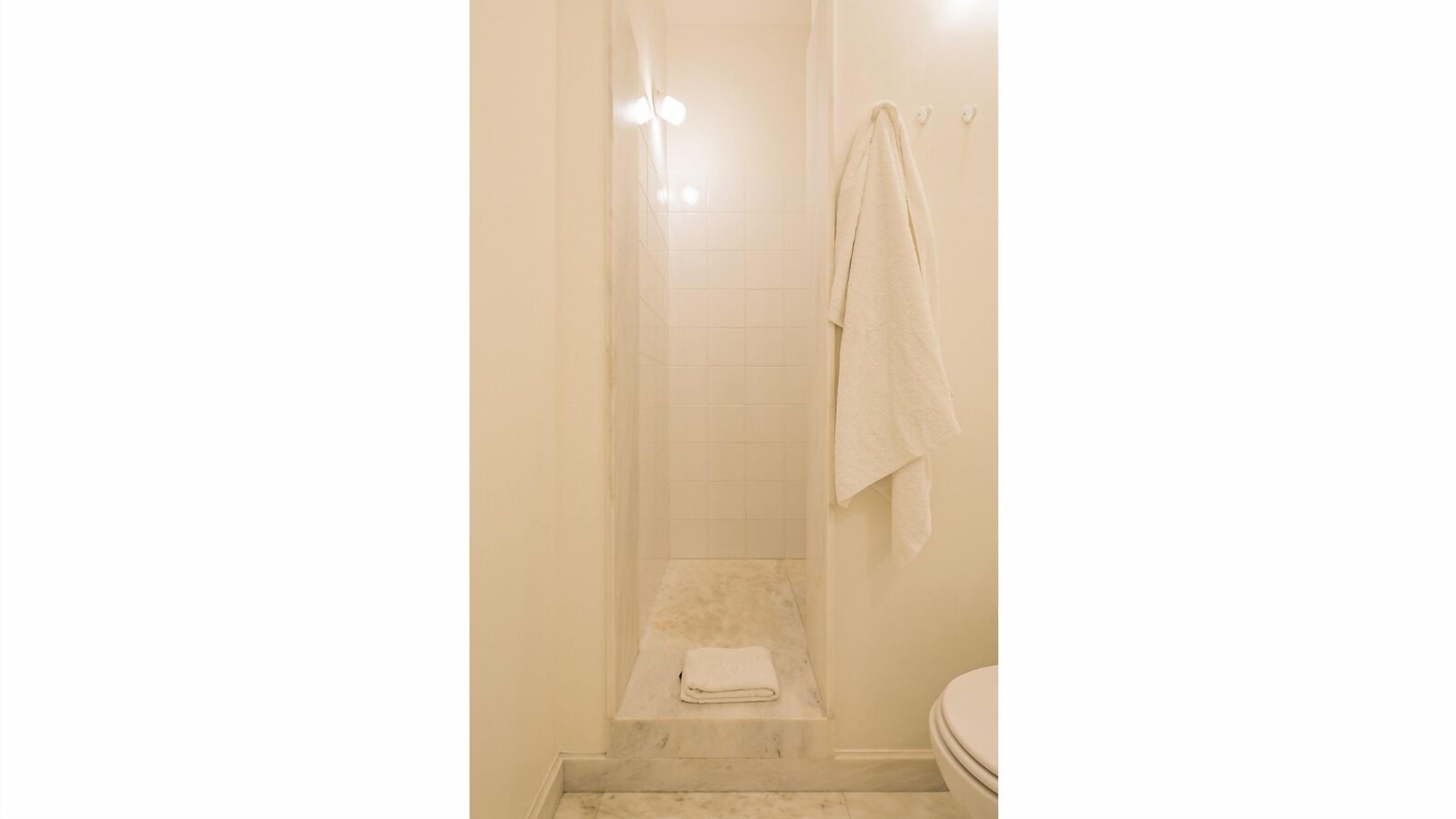 Un baño con ducha, inodoro y una toalla colgada en la pared.