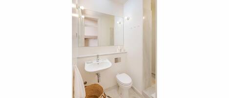 A bathroom with a white sink, toilet, and a mirror above the sink.