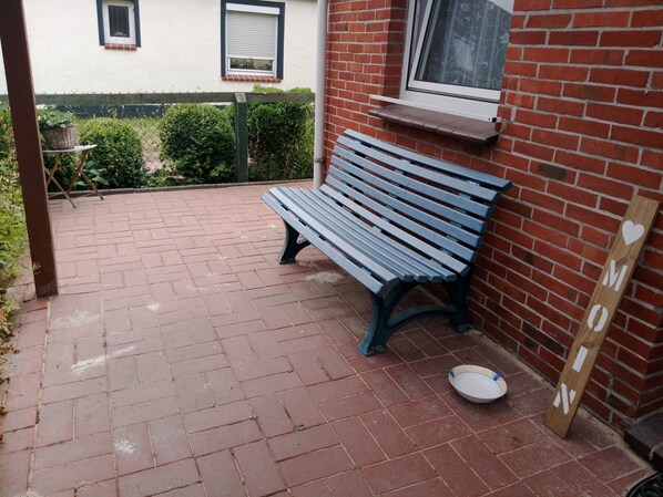 A brick patio with a wooden bench and a white bowl.