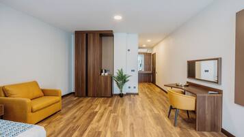 Une chambre d’hôtel moderne avec un plancher en bois, un canapé, un bureau et un miroir.