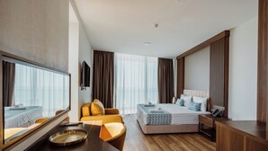 A hotel room with a bed, a sofa, a desk, and a large mirror. - Hotel Navi (Batumi)