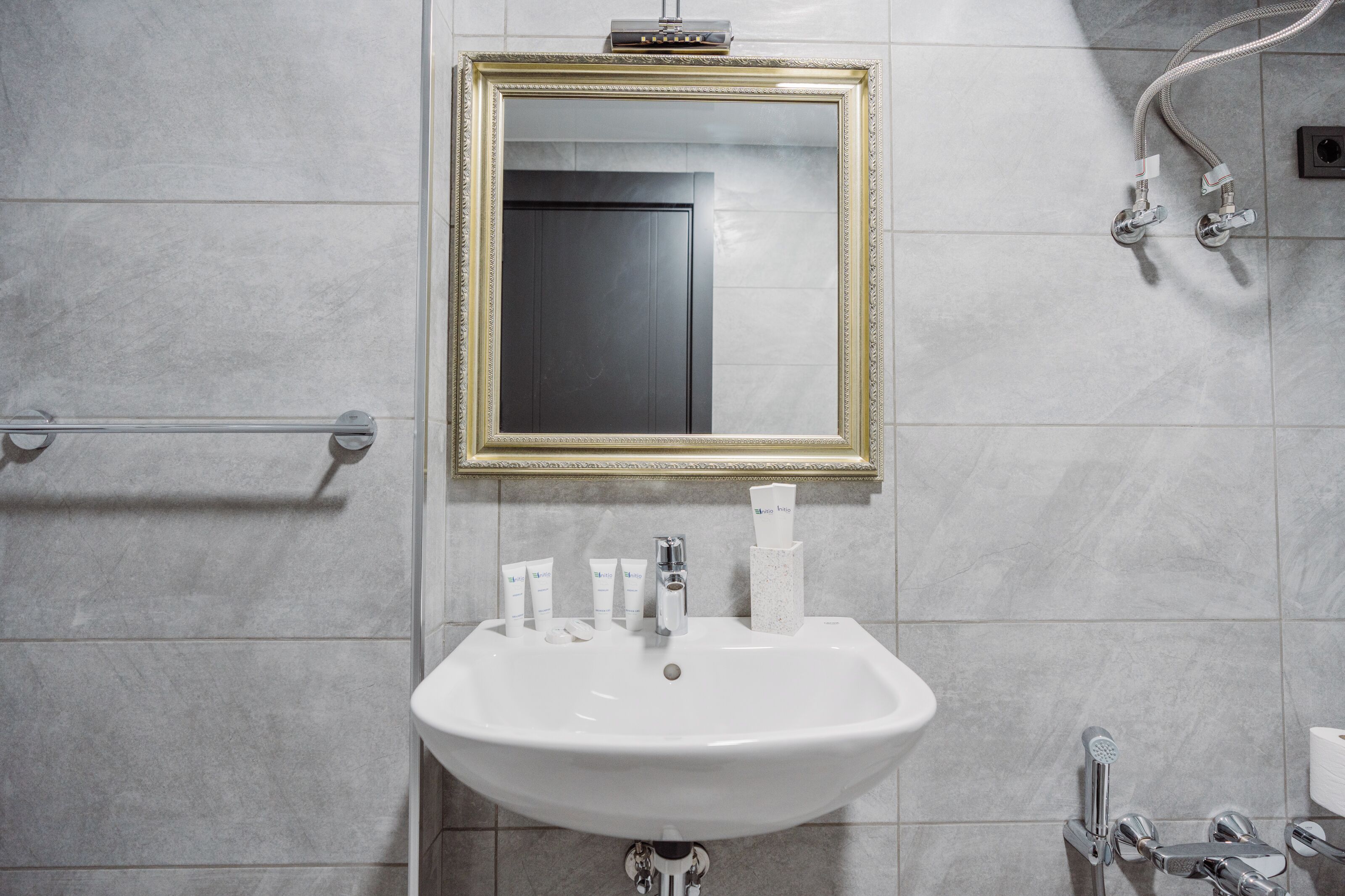A bathroom with a white sink, a gold-framed mirror, and a towel rack.