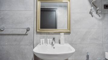 A bathroom with a white sink, a gold-framed mirror, and a towel rack.