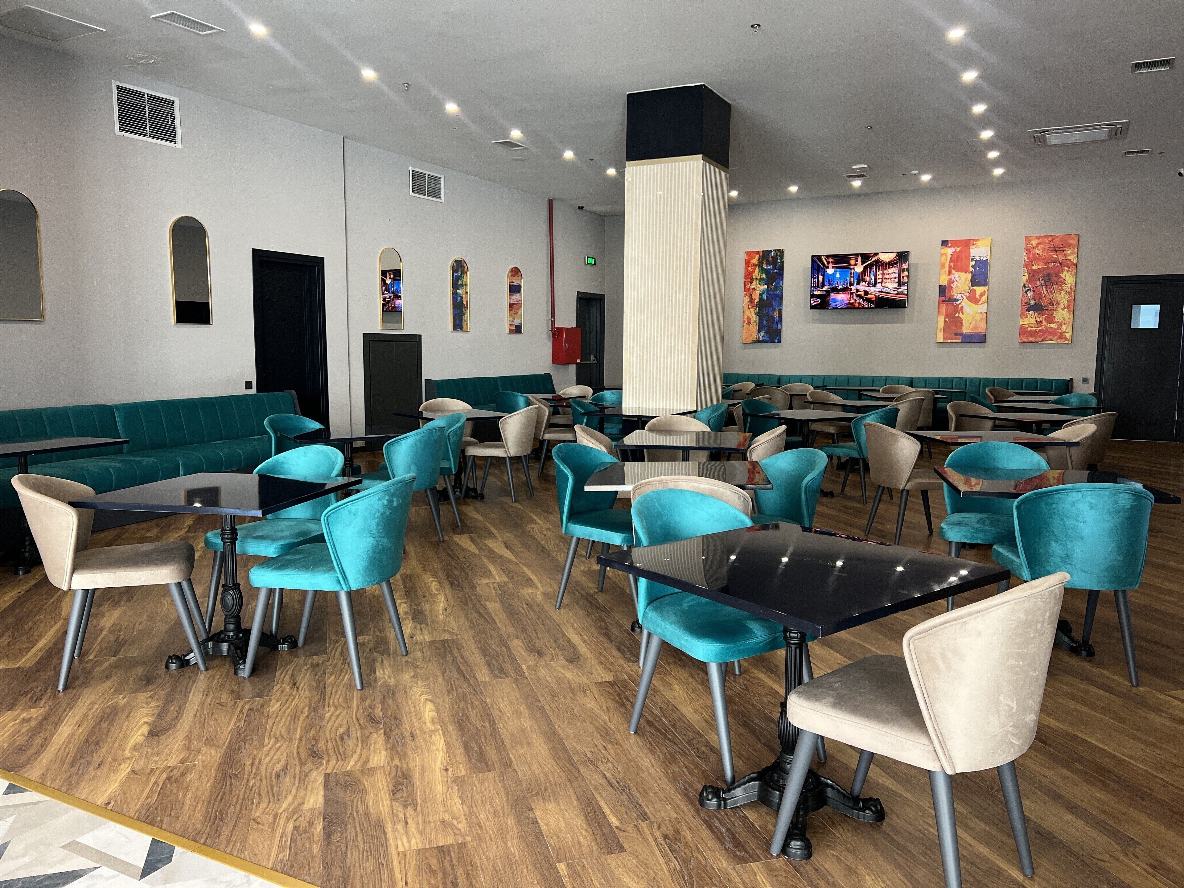 A restaurant with teal and beige seating, wooden flooring, and a modern interior design.