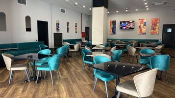 A restaurant with teal and beige seating, wooden flooring, and a modern interior design.