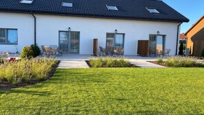 A modern two-story house with a flat roof, large windows, and a well-maintained lawn. - Comfortable, 2-level holiday apartment (Grzybowo)