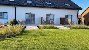 A modern two-story house with a flat roof, large windows, and a well-maintained lawn. - Comfortable, convenient holiday apartment (Grzybowo)