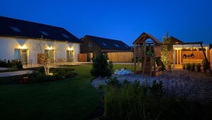 A residential property with a well-maintained lawn, a wooden play structure, and a covered area with string lights. - Comfortable, convenient holiday apartment (Grzybowo)