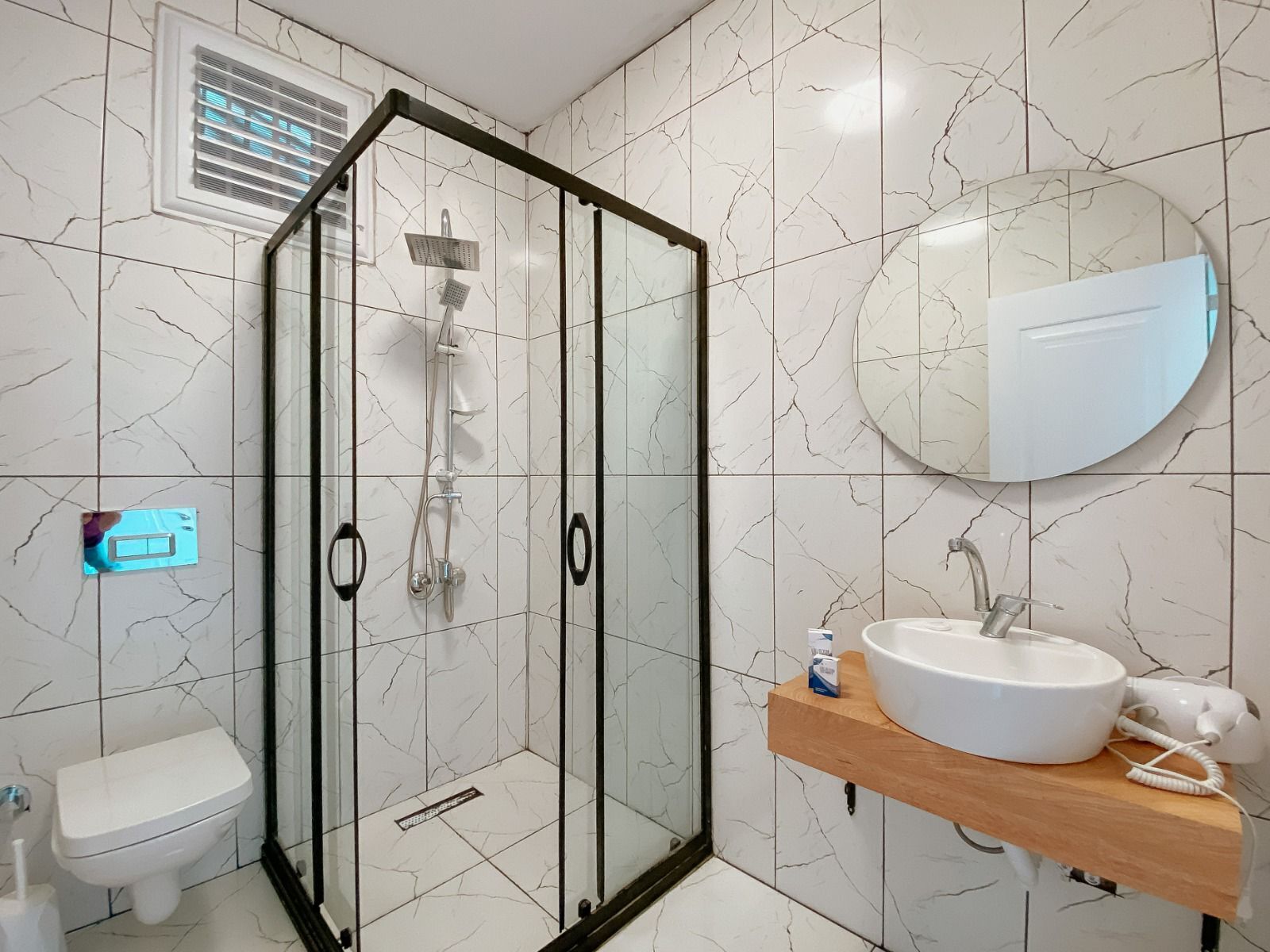A modern bathroom with a glass-enclosed shower, a toilet, a sink with a mirror, and a towel rack.