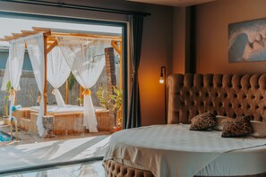 Un dormitorio con una cama grande, vistas a una terraza de madera y una lámpara fijada a la pared.