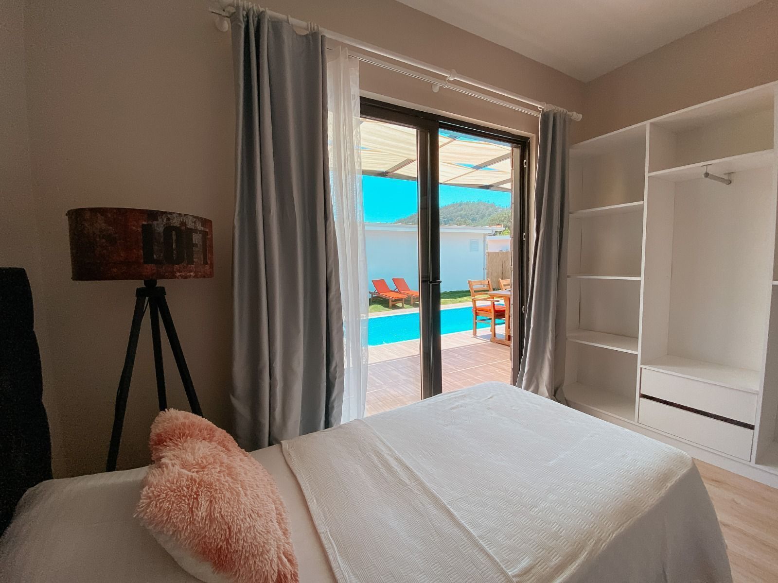 Une chambre avec un lit, un tableau, une lampe et une vue sur une piscine extérieure.