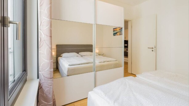 Une chambre à coucher avec un lit, un meuble avec miroir et une porte.