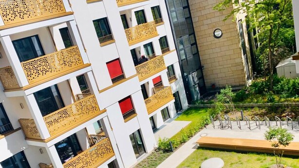 A modern apartment building with balconies, a courtyard with seating, and a small garden area. - ENJOY new flat in MITTE for couples and families
 (Berlin)