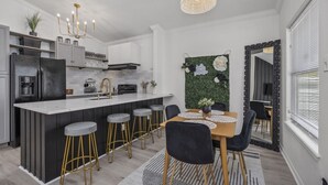 Una cocina moderna con una isla central, taburetes de bar y una mesa de comedor con sillas.
