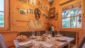 A wooden interior with a dining table set for four, framed pictures on the walls, and a large world map. - Log Cabin Forest Chalets (Podcetrtek)