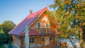 A wooden cabin with a red roof, a balcony, and a small porch area. - Log Cabin Forest Chalets (Podcetrtek)