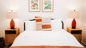 A hotel room with a bed, two nightstands, two lamps, and two framed floral paintings on the wall. - Artist Retreat | Near Downtown, Stadium & UGA (Athens)