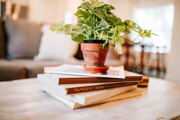 A stack of books with a potted plant on top, placed on a wooden table.