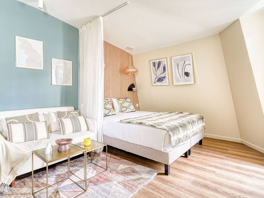 Un dormitorio con cama, sofá, mesa de centro y mesita de noche.