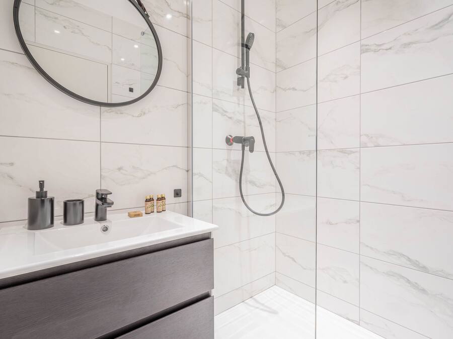 Une salle de bain moderne avec un lavabo en marbre blanc, un miroir et une douche.