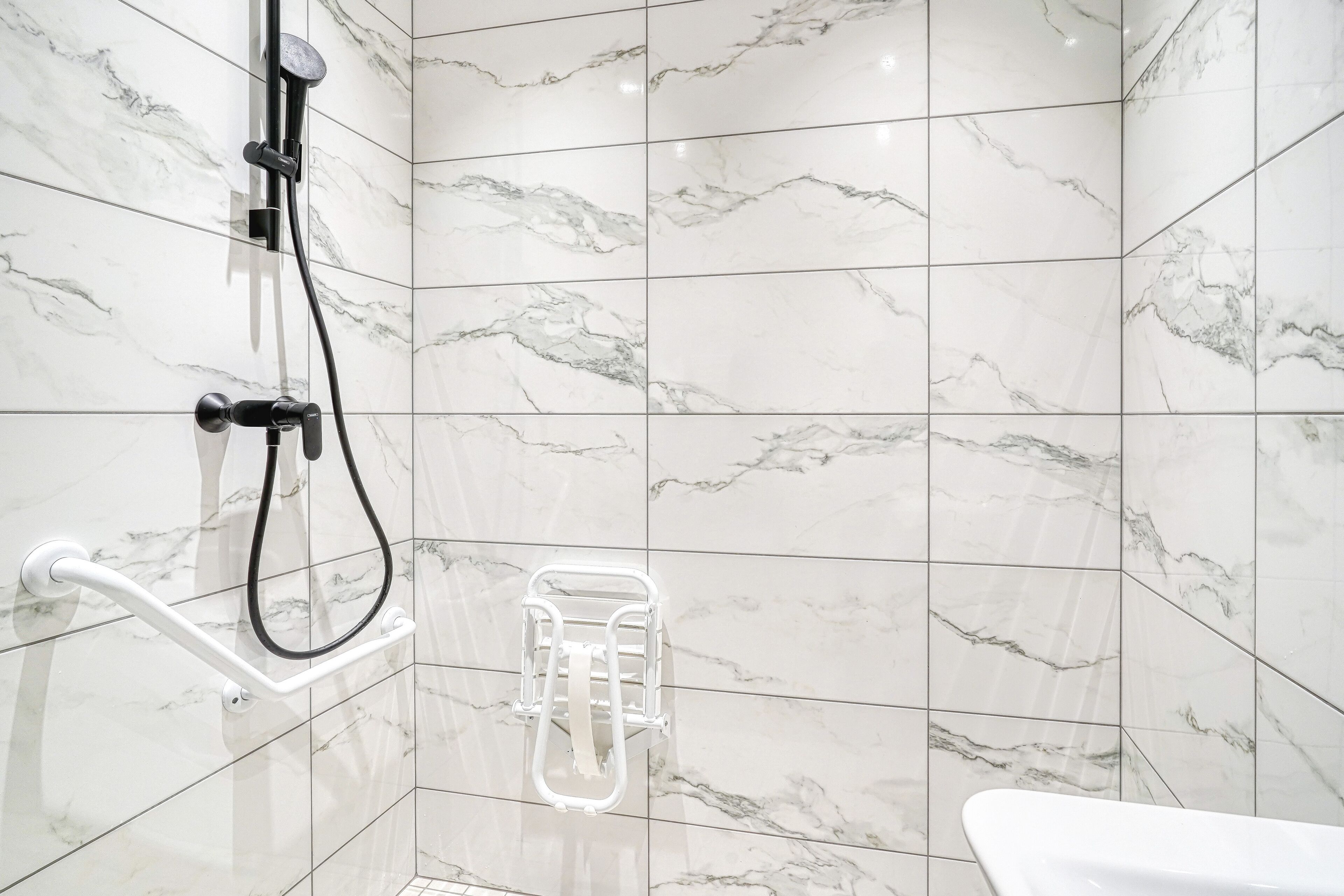 A bathroom with a shower, grab bar, and towel rack.