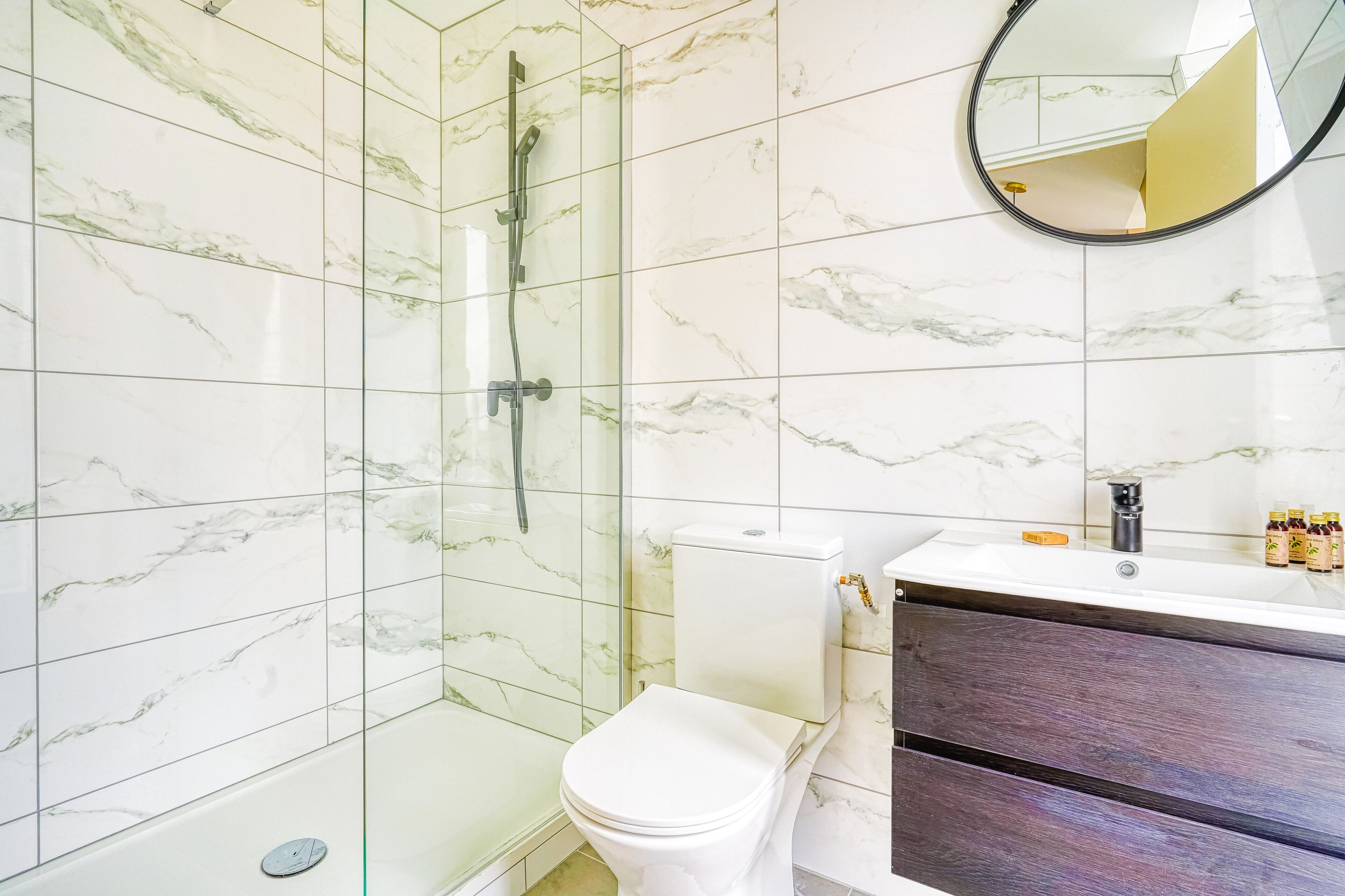 A bathroom with a glass-enclosed shower, a white toilet, and a vanity with a dark wood finish.