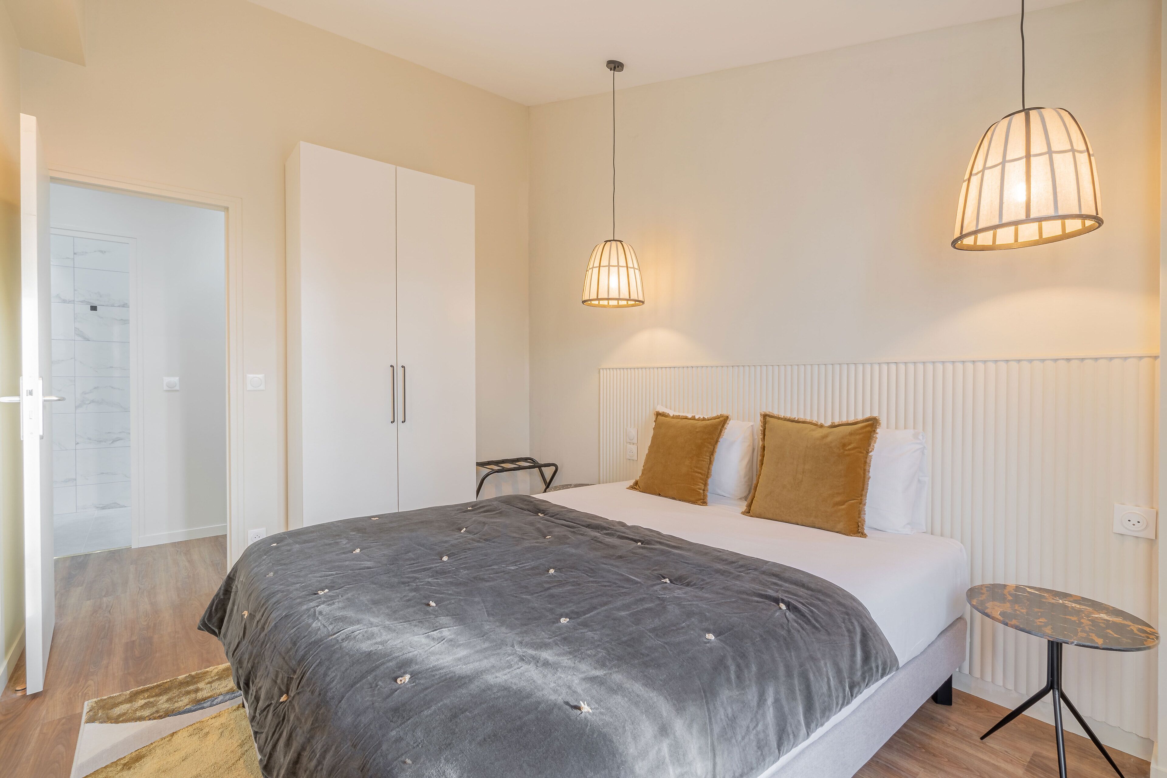 Ein Schlafzimmer mit einem Bett, einem Nachttisch und zwei Pendelleuchten.