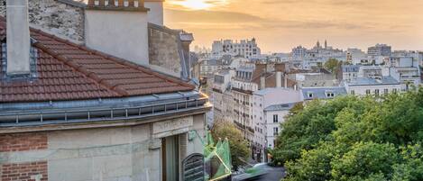 Un paisaje urbano que combina edificios modernos e históricos, cielo despejado y una calle arbolada.