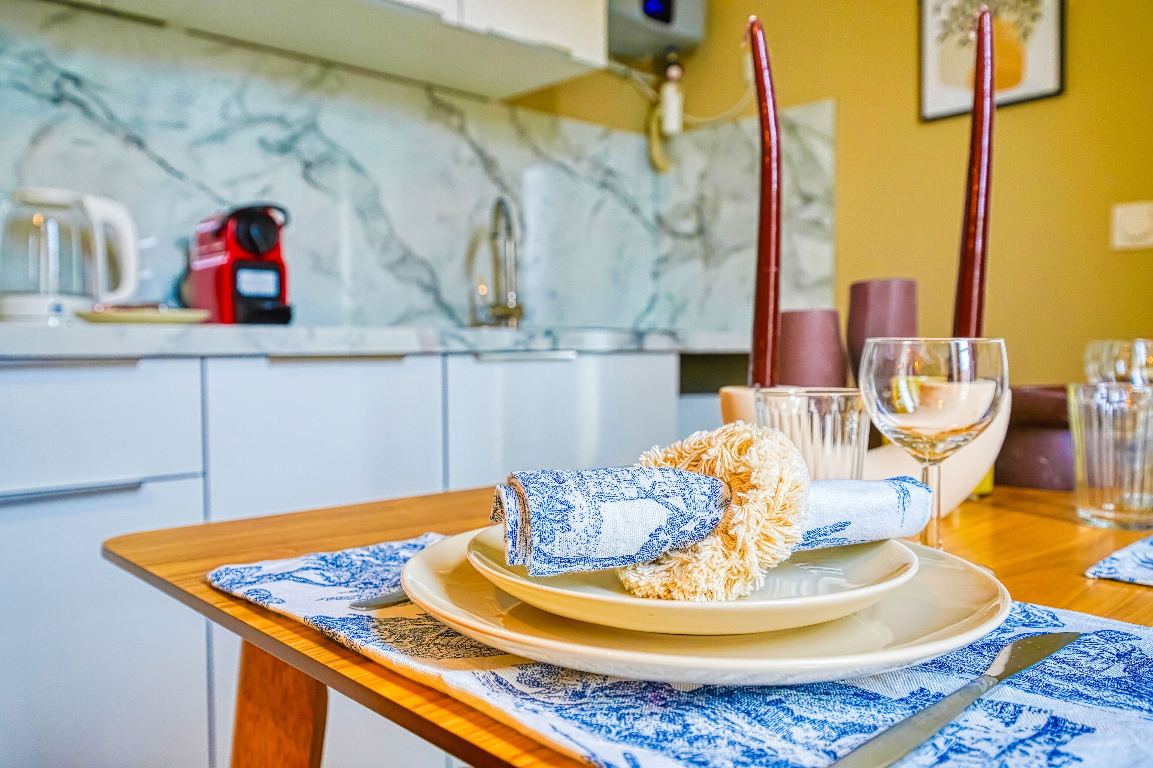 A dining table set with plates, a folded napkin, and a glass of white wine.