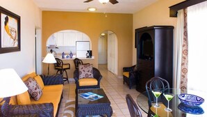 A living room with a sofa, chairs, a coffee table, and a dining area with a table and chairs. There is a kitchen visible through an archway. - The Best of Cabo San Lucas! (cabo san lucas)