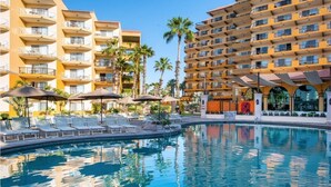 A hotel with multiple balconies, a swimming pool, and palm trees. - The Best of Cabo San Lucas! (cabo san lucas)