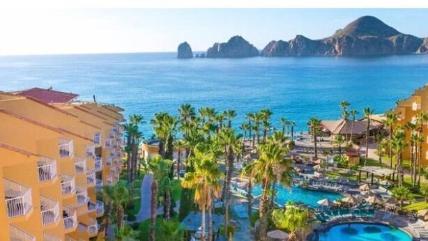 A resort with a pool area surrounded by palm trees and a view of the ocean. - The Best of Cabo San Lucas! (cabo san lucas)