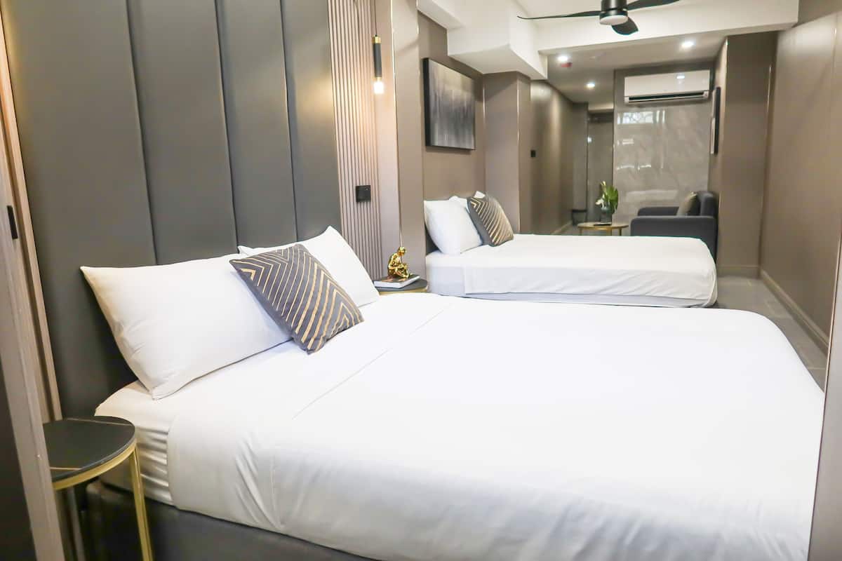 A modern hotel room with two beds, a small table, and a seating area.