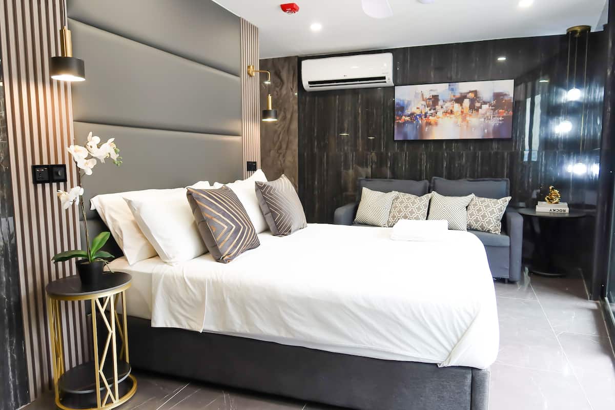 A modern bedroom with a large bed, a side table, and a mounted TV.
