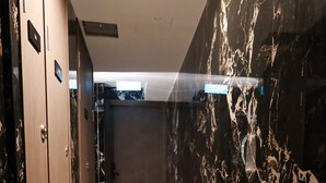 A marble-floored hallway with wooden lockers and a mirrored wall. - Recharge Residences  (Singapore)