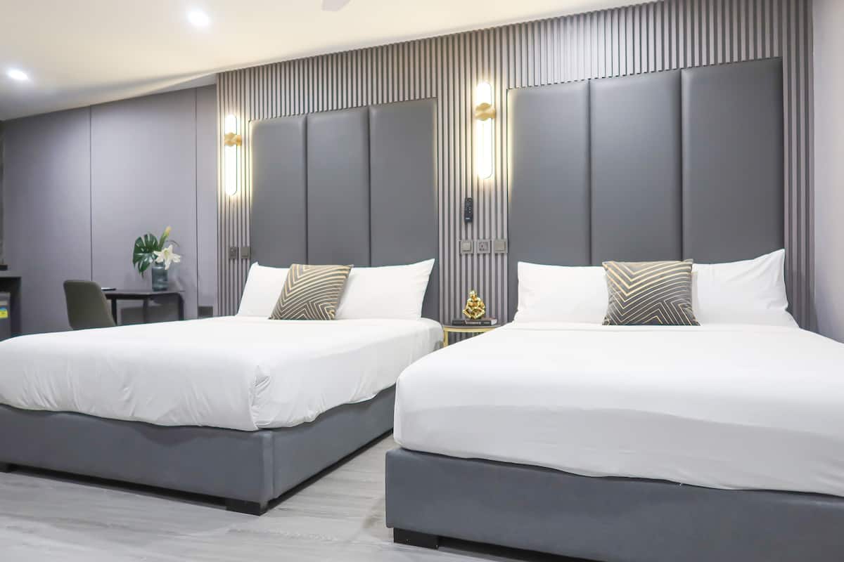 A modern hotel room with two beds, a small desk, and a decorative plant.