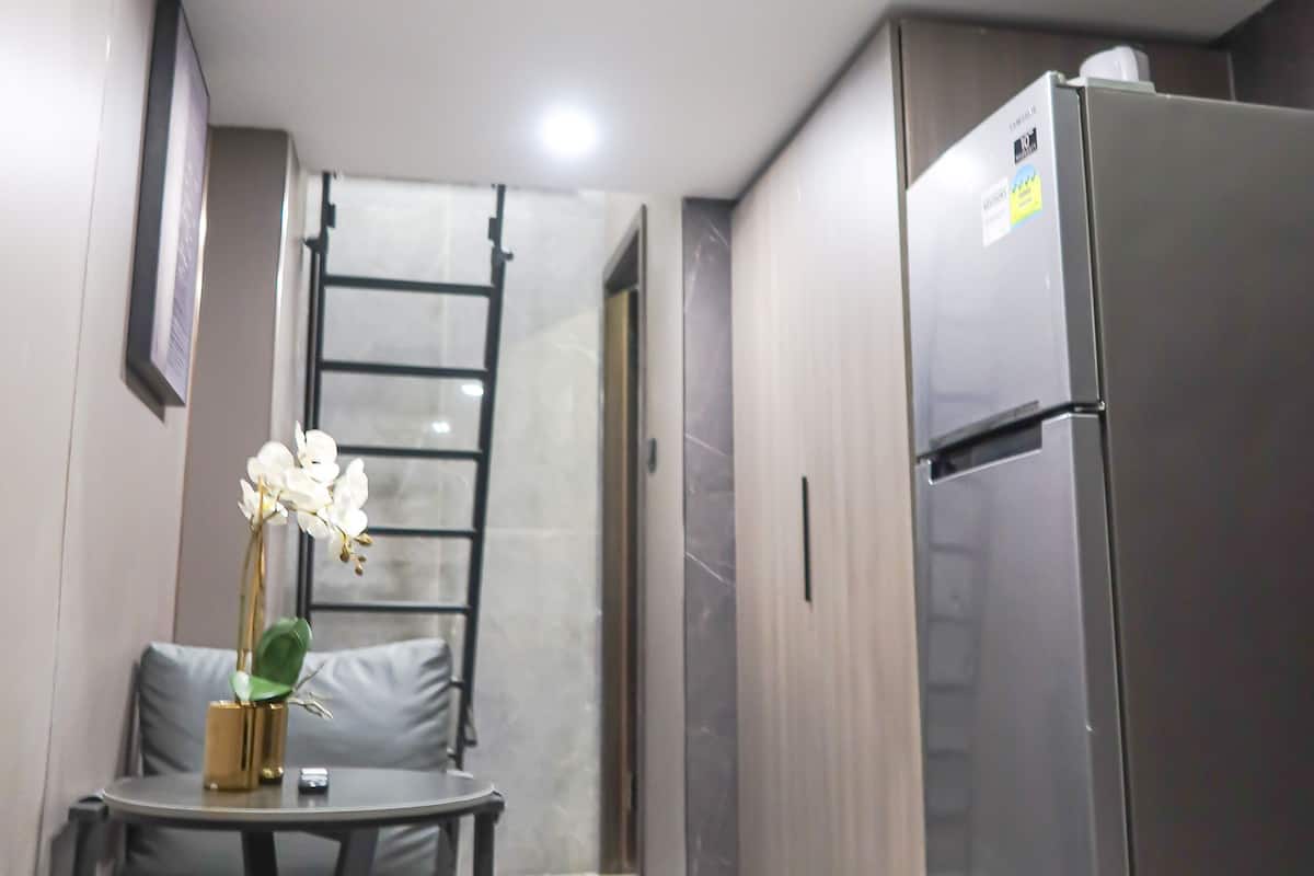 A modern kitchen with a stainless steel refrigerator, a dining table with chairs, and a staircase leading to an upper level.