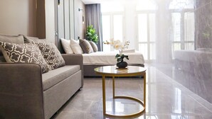 A modern living room with a sofa, a round coffee table, and a bed with a plant on it. - Recharge Residences  (Singapore)