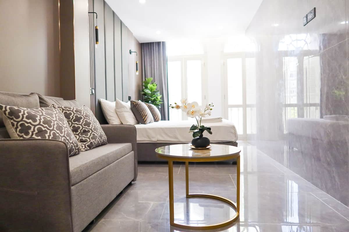 A modern living room with a sofa, a round coffee table, and a bed with a plant on it.