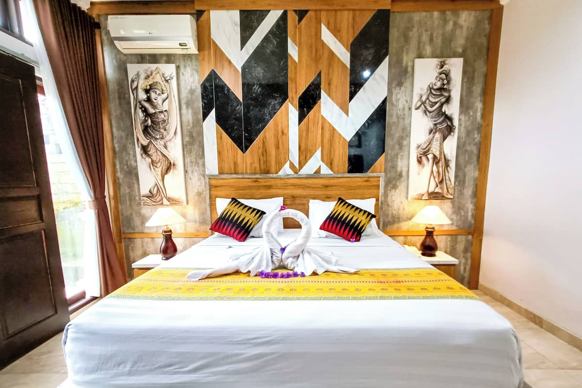 A hotel room with a large bed, two wall-mounted lamps, and a decorative headboard with geometric patterns.
